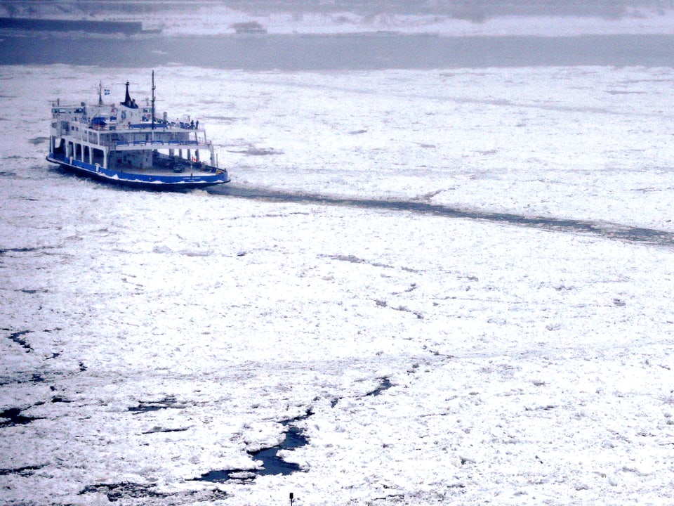Blick auf den zufrierenden St. Lawrence River in Quebec. Ein Passagierdampfer durchpflügt die frische Eisdecke.