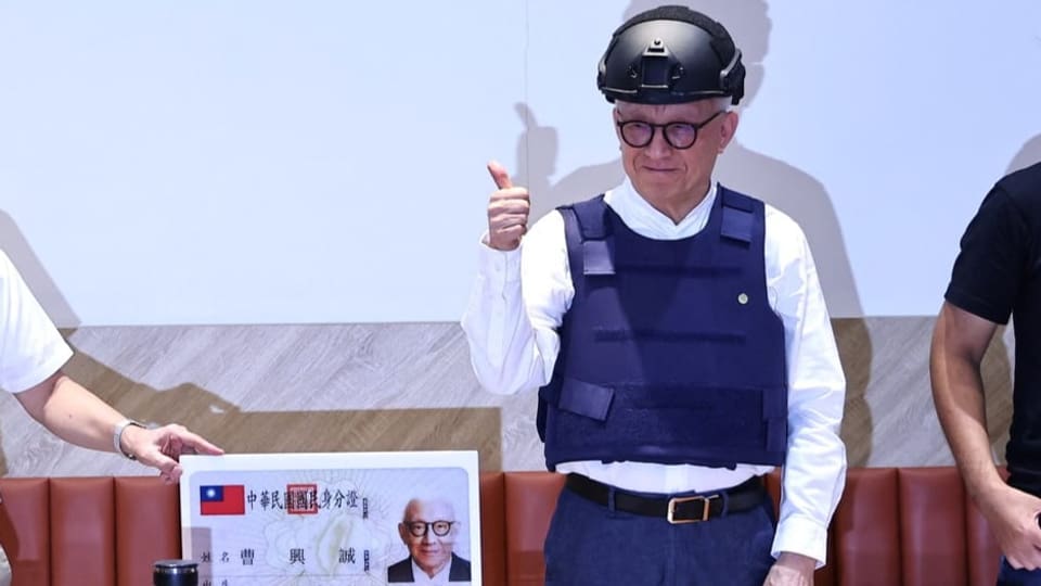 Mann mit schwarzer Brille trägt über weissem Hemd blaue Schutzweste und schwarzem Helm.