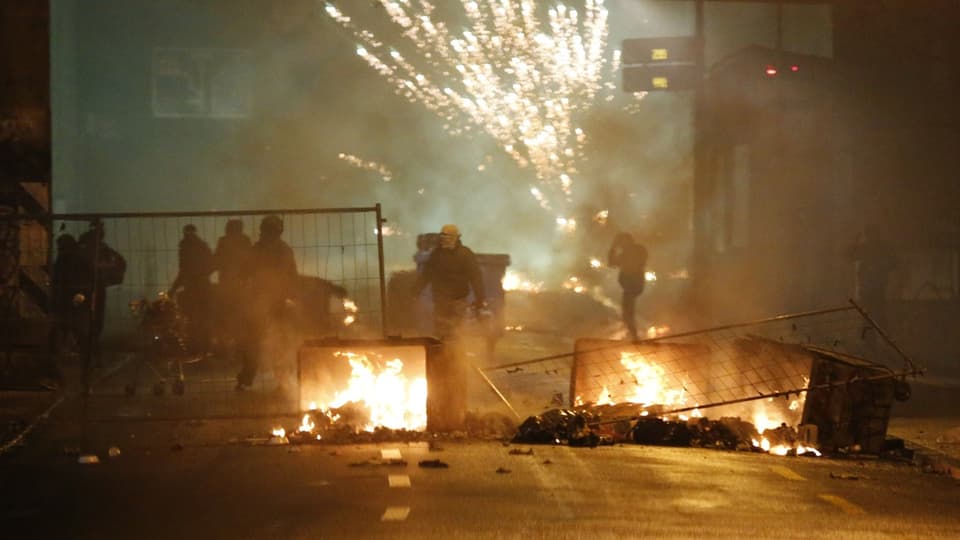 Strassensperre mit Feuer und Silvesterfeuerwerk, Menschen im Hintergrund