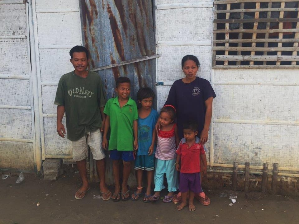 Ein Mann, eine Frau und vier Kinder vor einem Haus.