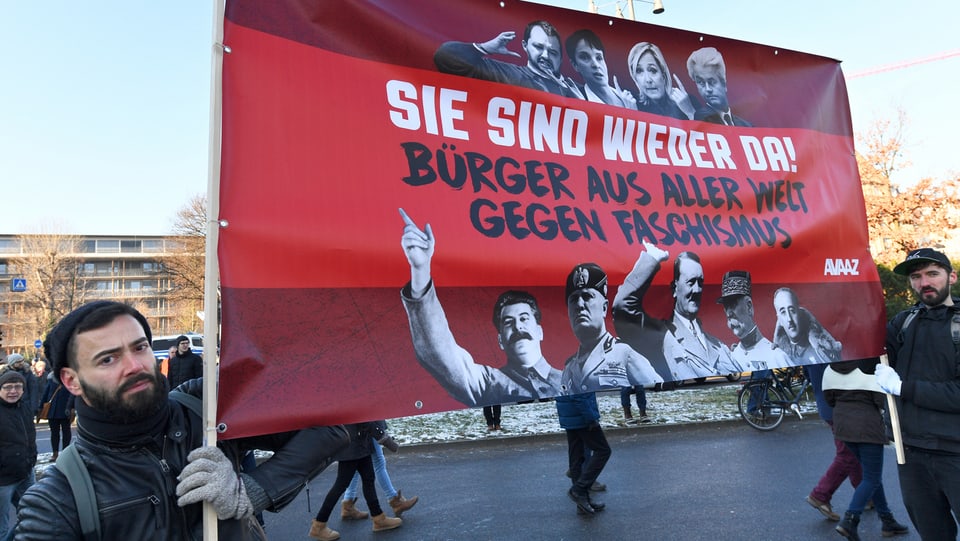 Plakat von Demonstranten mit Bildern von Faschisten wie Hitler und Mussolini.