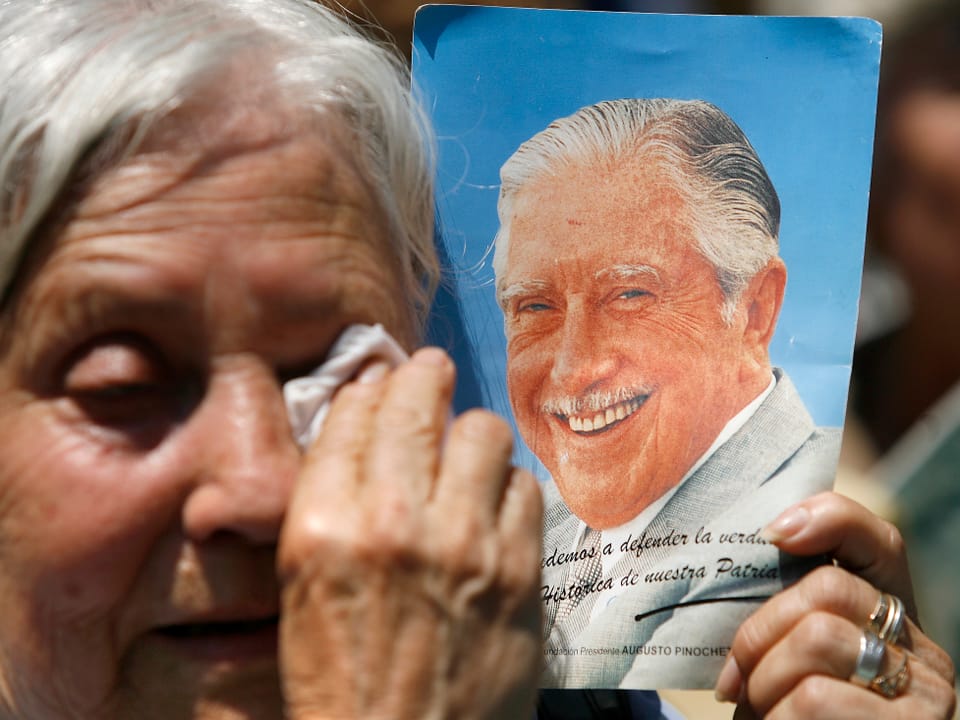Eine Pinochet-Anhängerin weint mit einem Bild des Diktators in der Hand.