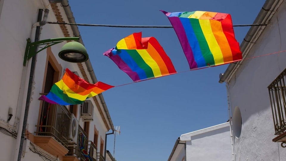 Regenbogenfahnen in einer Strasse in Málaga.
