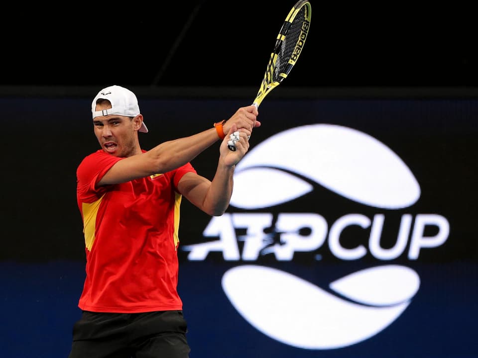 Rafael Nadal spielt eine beidhändige Rückhand vor dem ATP-Cup-Logo.