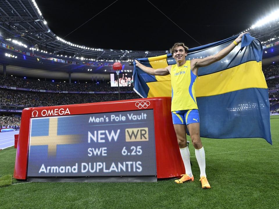 A pole vaulter holding a Swedish flag celebrates a world record at the Olympics.