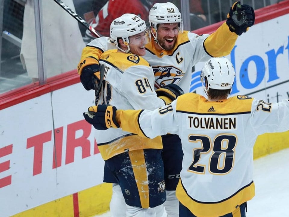 Die Freude ist ihnen ins Gesicht geschrieben Tanner Jeannot, Roman Josi und Eeli Tolvanen liegen sich auf dem Eis in den Armen.