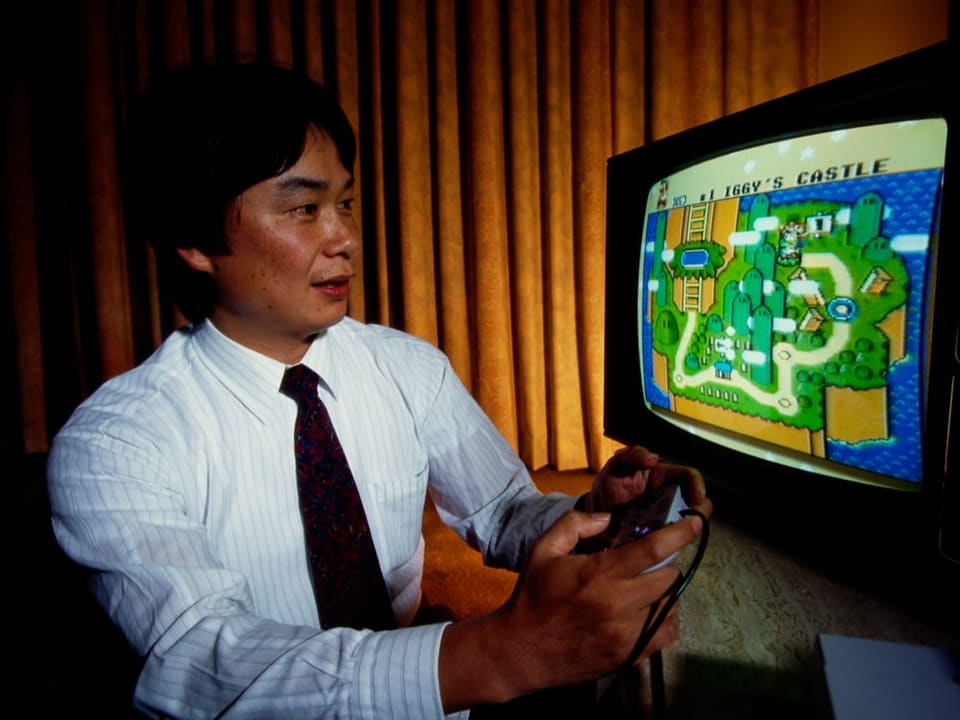Mann mit Krawatte spielt ein Videospiel in Pixelgrafik auf altem Röhrenfernseher