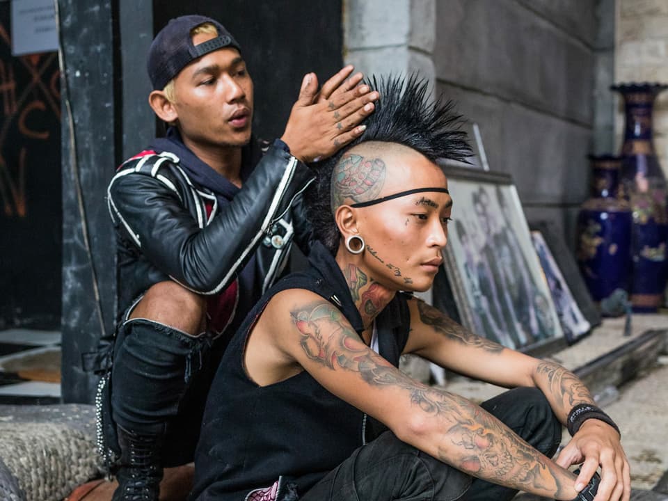 Ein Punk frisiert seinem Kollegen einen Irokesen.
