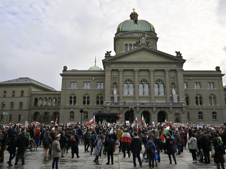 Menschen protestieren vor dem Bundeshaus mit Plakaten und Iran-Fahnen.