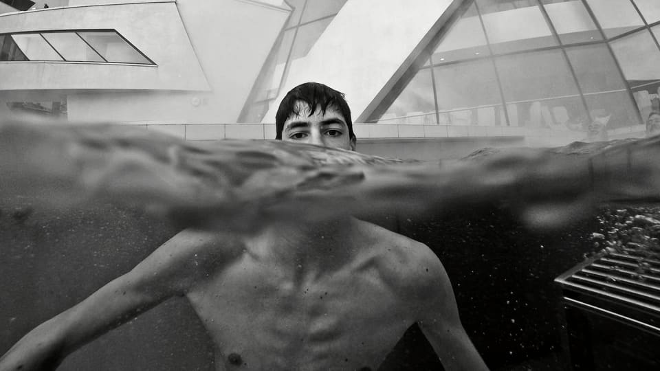 Schwarzweissaufnahme: Ein junger Mann in einem Schwimmbecken