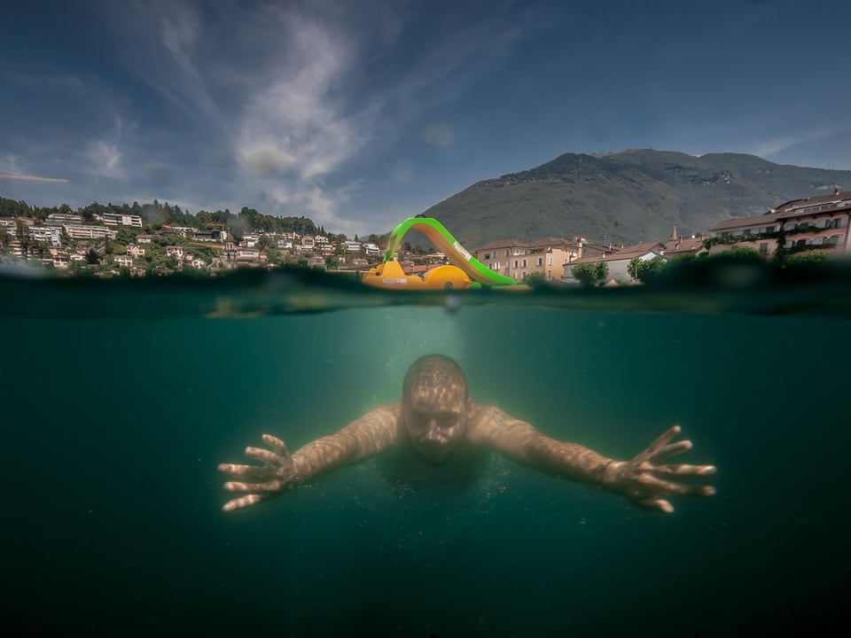 Ein Mann taucht unter einem Pedalo im Lago Maggiore (Langensee) bei Ascona.