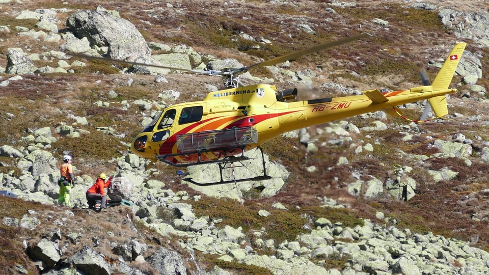 Ein gelber Helikopter hat einen künstlichen Stein mit Drahseil zur Startrampe geflogen.