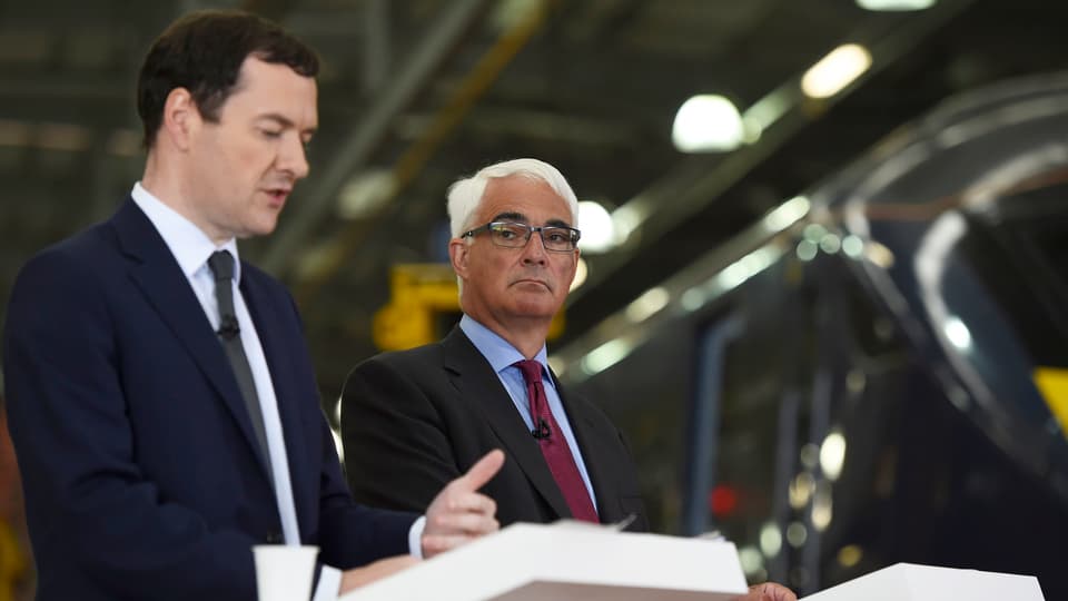 Osborne und Darling sprechen an zwei weissen Rednerpulten in der Halle einer Zugfabrik.