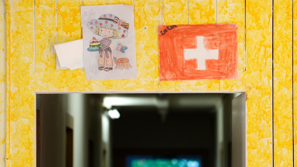 Eingang in ein Asylzentrum mit zwei Kinderzeichnungen.