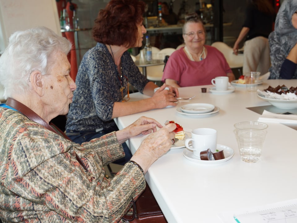 Senioren an Tisch bei Café und Kuchen.