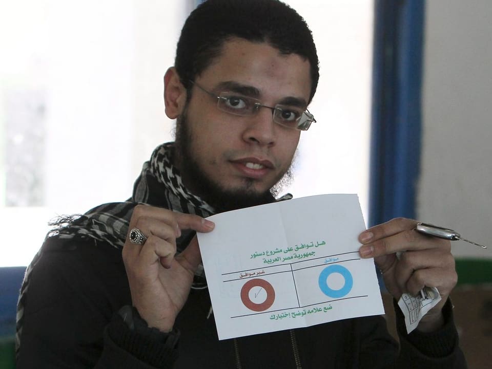 Ein Wähler zeigt seinen Abstimmungszettel in die Kameras.
