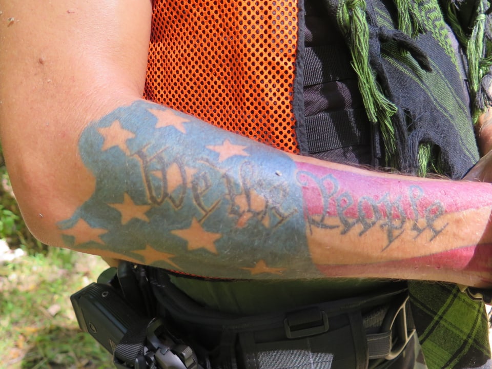 Ein Tattoo: We the People. Hinter der Schrift ist die Amerika-Fahne.