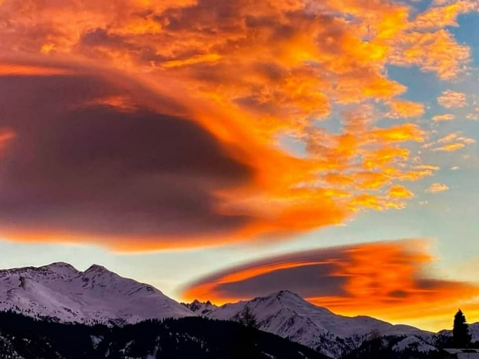 Ufoartige, linsenförmige, grosse Wolke über Alpental, die rot leuchtet.