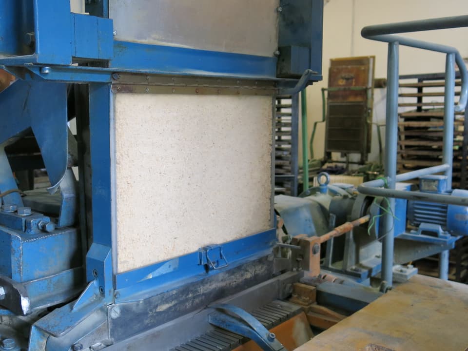 Eine blaue Maschine, gefüllt mit Zündhölzern hinter einer Scheibe. 