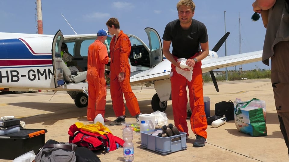 Eine Crew vor einem kleinen Flugzeug.