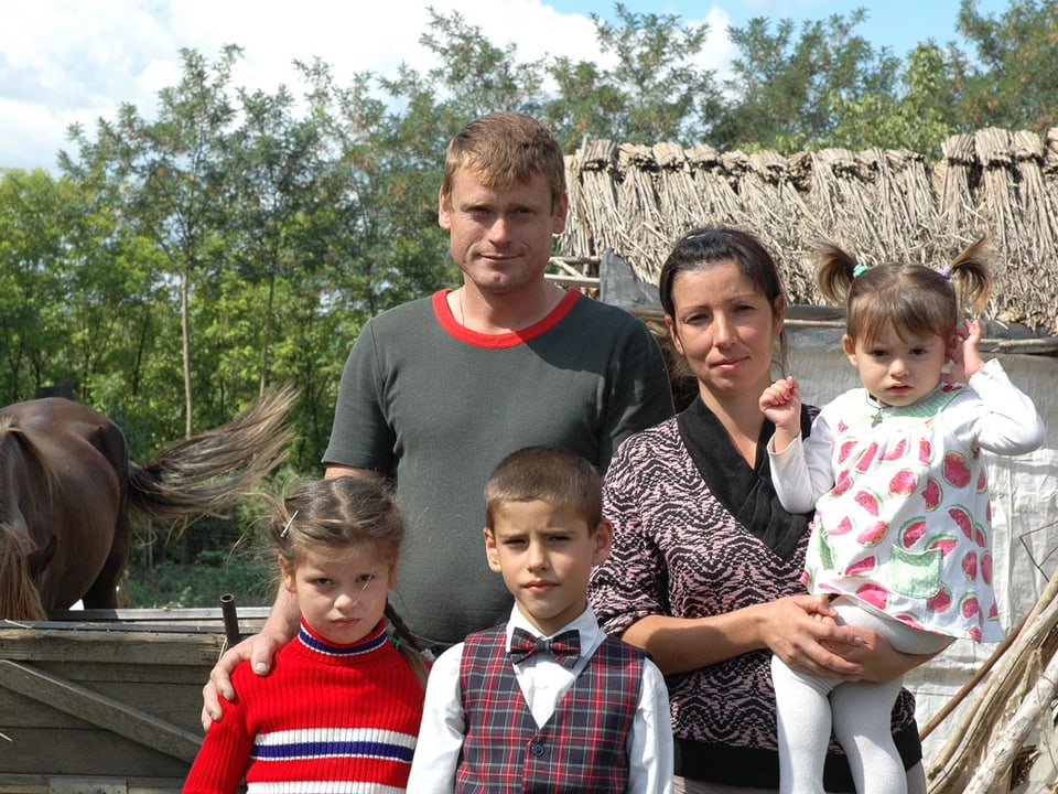 Eine Bauernfamilie mit drei Kindern posiert fürs Foto.