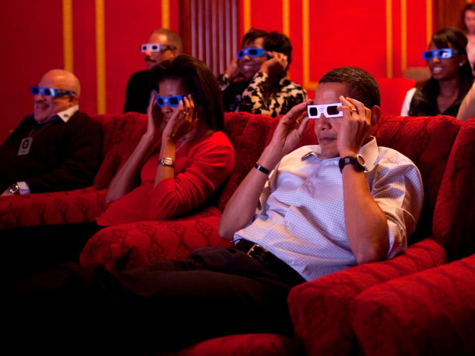 Michelle und Barack Obama sitzen mit 3-D-Brillen in einem Kino. 