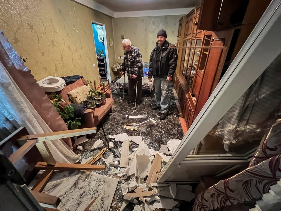 Zwei Männer in der beschädigten Wohnung