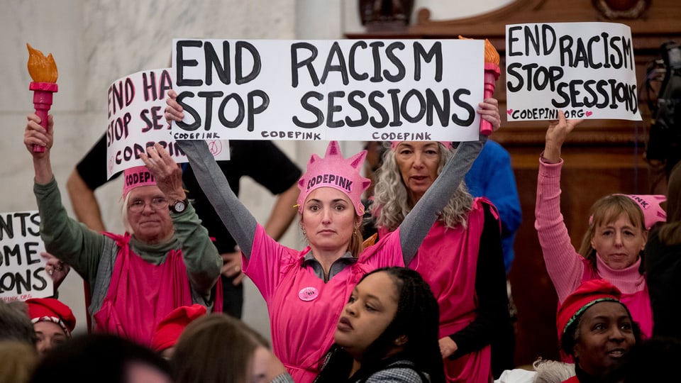 Mehrere Frauen in pinkfarbener Kleidung halten Plakate in die Höhe.