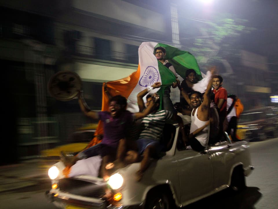 Indische Cricket-Fans sitzen auf einem Ambassadoren und schwenken die Nationalflagge.