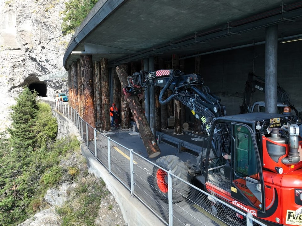 Máquina florestal move troncos de árvores no caminho da montanha perto da saída do túnel.
