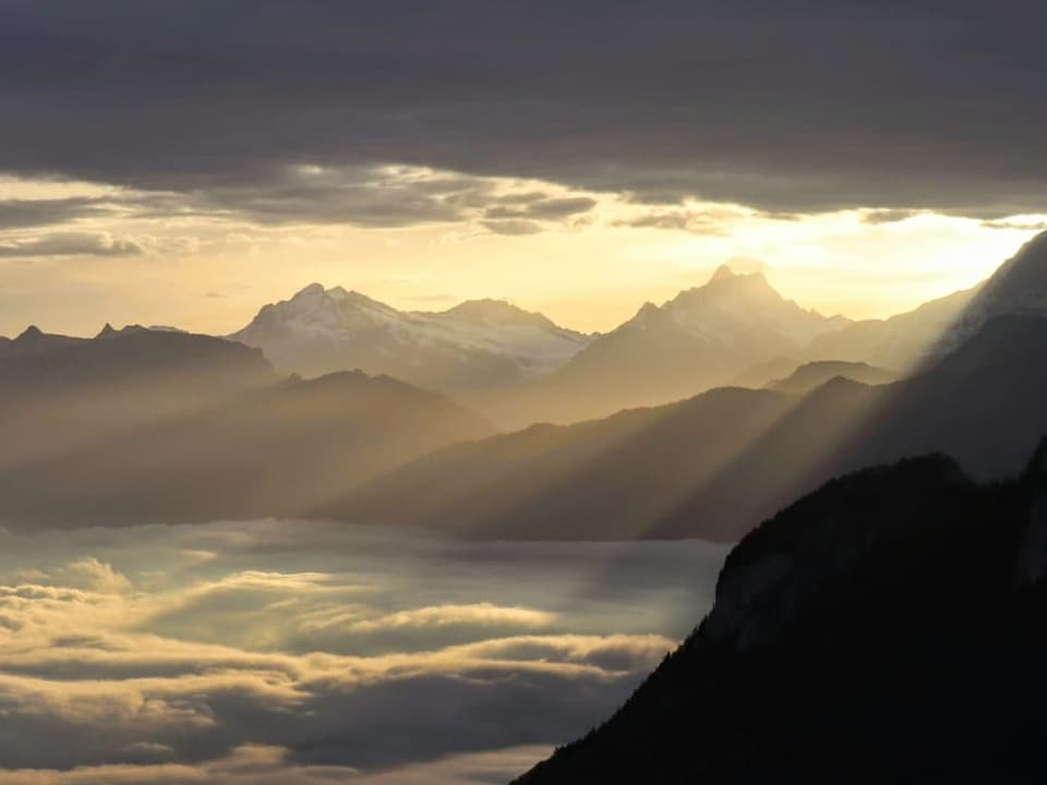 Blick auf ein Nebelmeer mit Wolken darüber. Dazwischen scheint die Sonne.