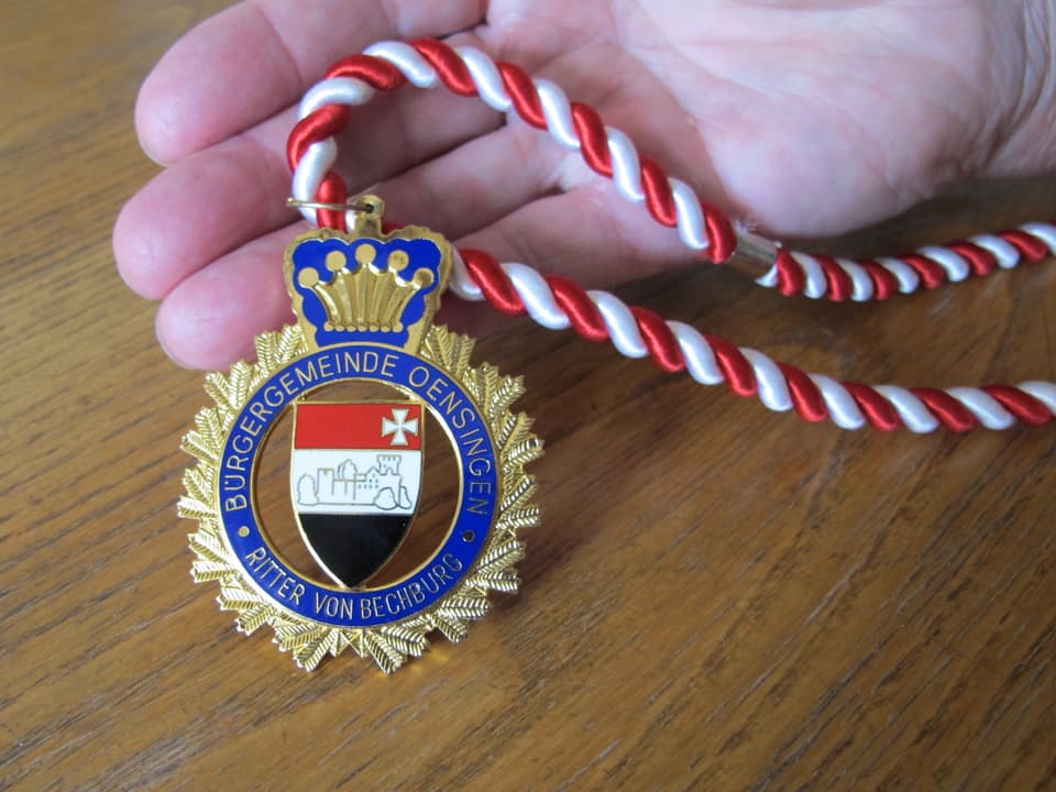 Medaille an einem rot-weissen Bändel.