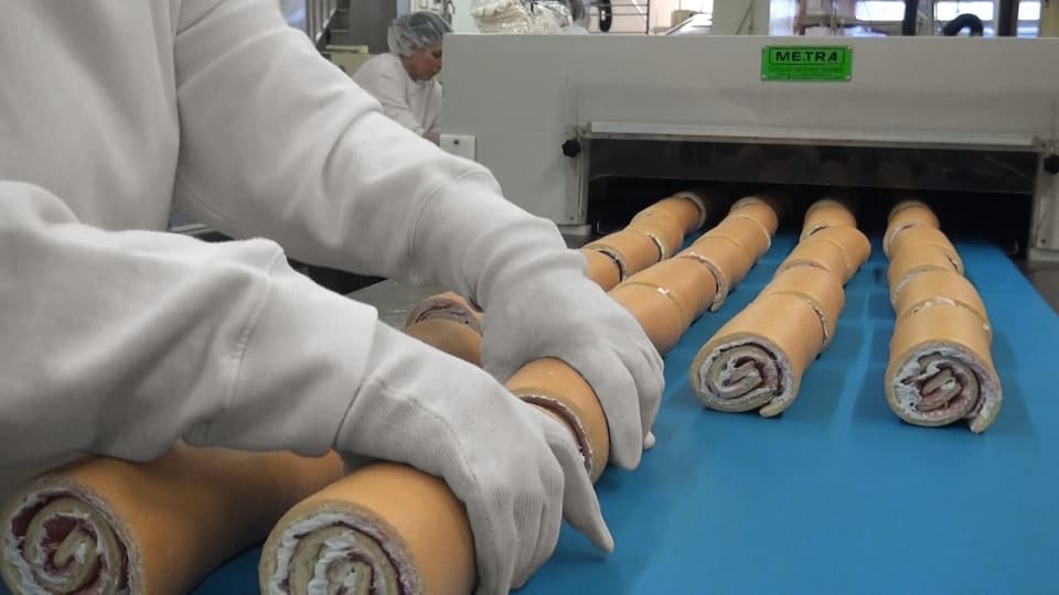 Industrielle Produktion von Rouladen, zwei Hände mit weissen Handschuhen 