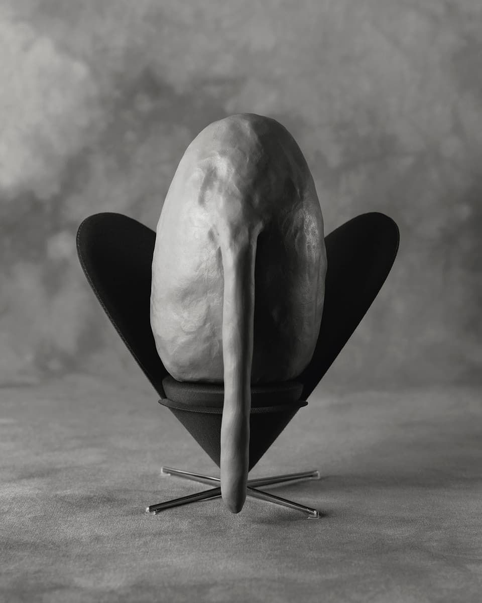 Ein Ei mit Rüssel sitzt auf eiem Stuhl, alles in grau.
