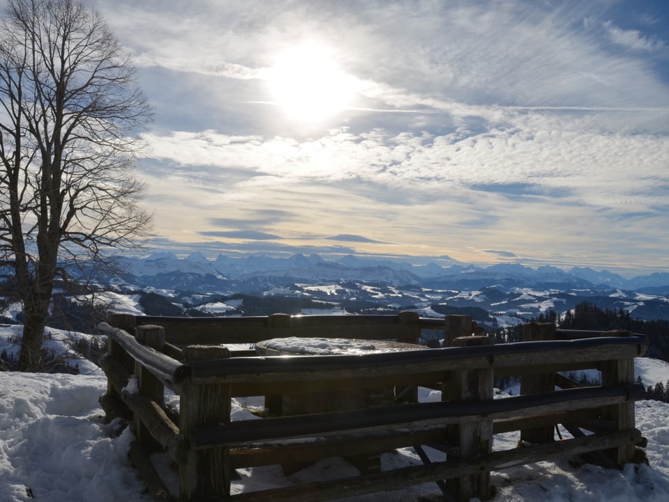 Vom sanften Emmentaler Hügel aus sieht man in die Berner Alpen. Am Himmel ziehen Wolkenfelder auf, und die Sonne scheint nur schwach durch die Schleierwolken durch.