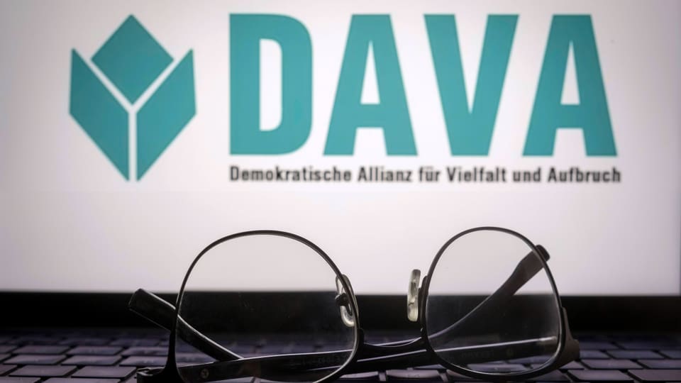 DAVA-Logo auf einem Laptop, im Vordergrund Tastatur mit Brille