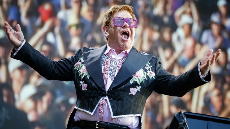 Elton John vor seinem Publikum auf einer Bühne.