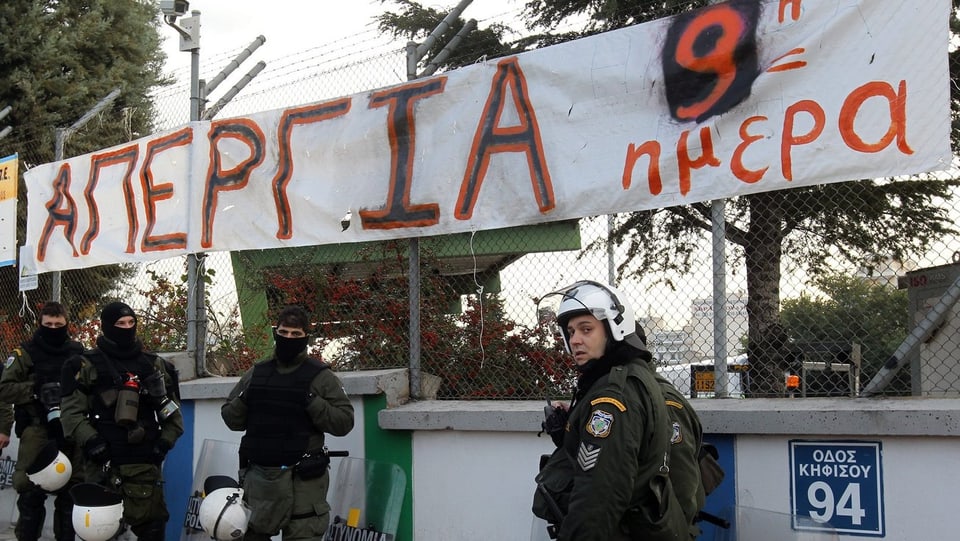 Griechische Polizisten, zum Teil vermummt, stehen vor dem gestürmten U-Bahn-Depot