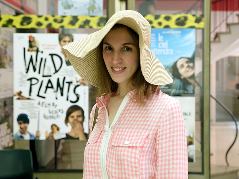 Junge Frau mit Hut vor dem Kino Ex*Rex