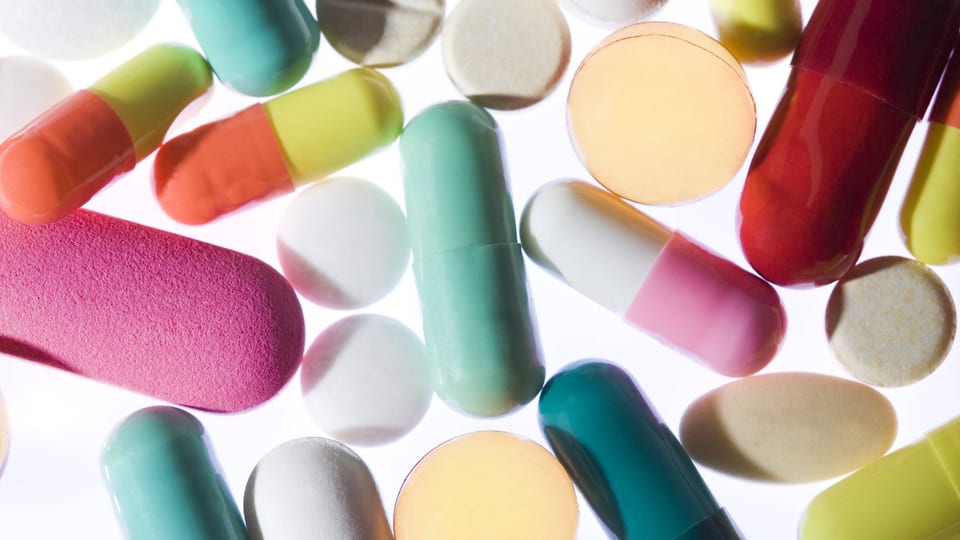 Verschiedene runde und bunte Pillen und Tabletten auf weissem Hintergrund.