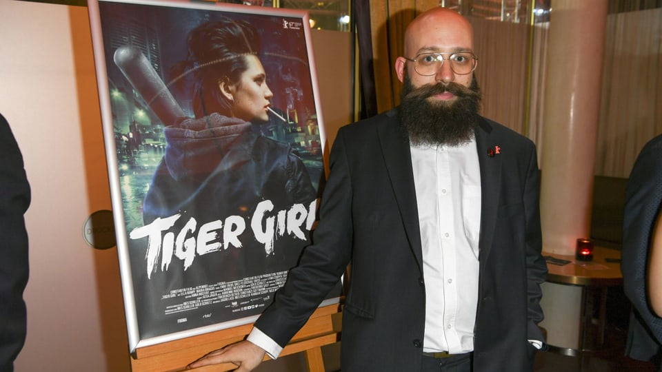 Der Regisseur Jakob Lass steht vor dem Filmplakat von "Tiger Girl".