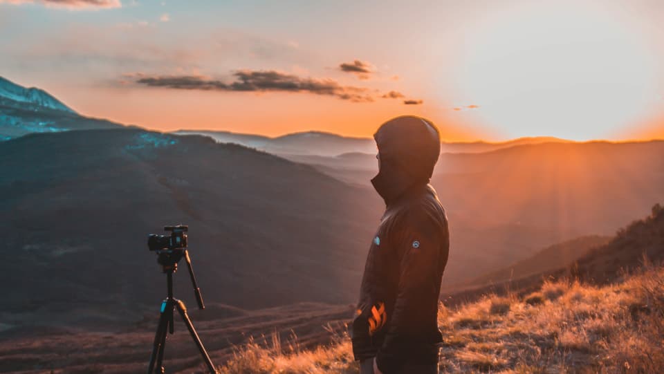 Sonnenaufgang mit Kamera und Mann um Vordergrund 