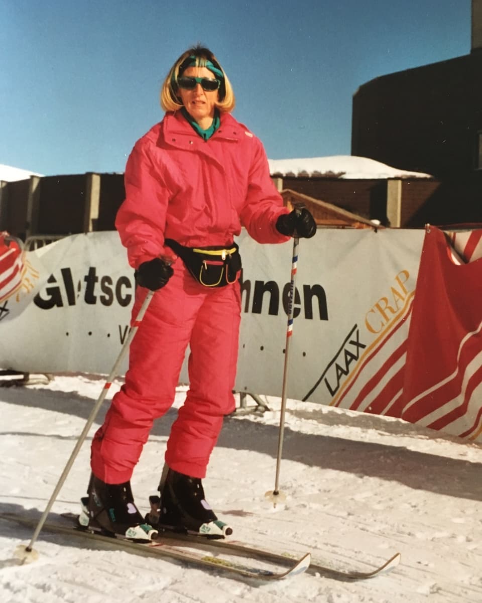 Eine Frau im pinken Einteiler-Skidress auf der Piste.