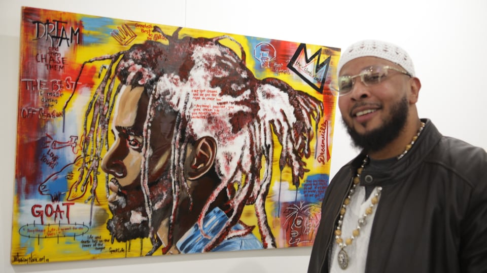 Leon Benson vor einem Portraitbild einer schwarzen Person.