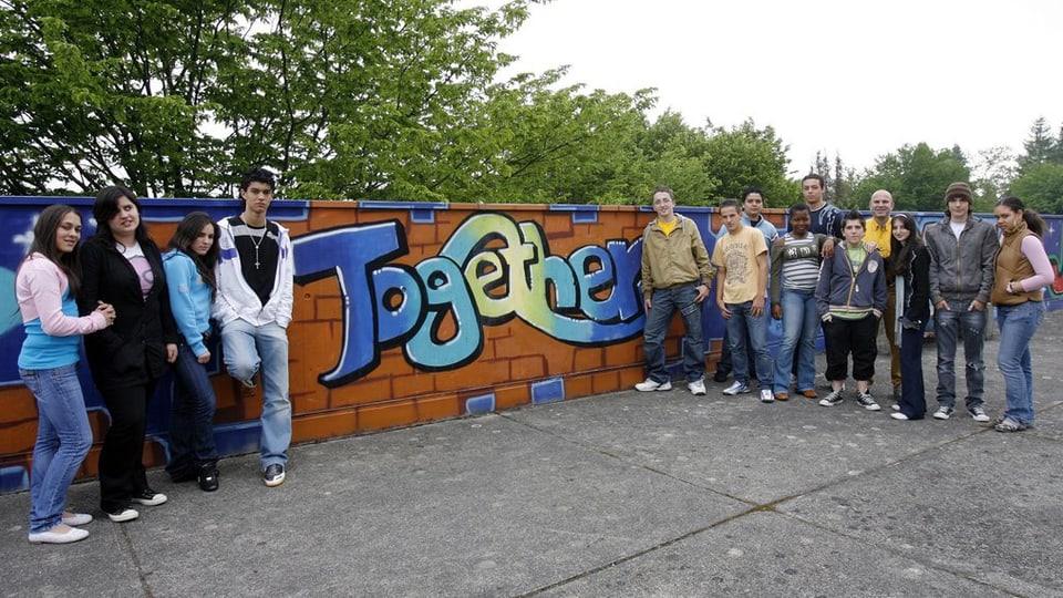 Mehrere Schüler stehen vor einer Mauer mit der Aufschrift Together