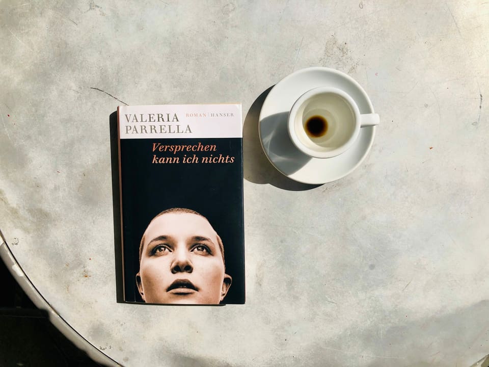 Der Roman «Versprechen kann ich nichts» von Valeria Parrella liegt auf einem Bistrotisch. Daneben steht eine leergetrunkene Espressotasse.