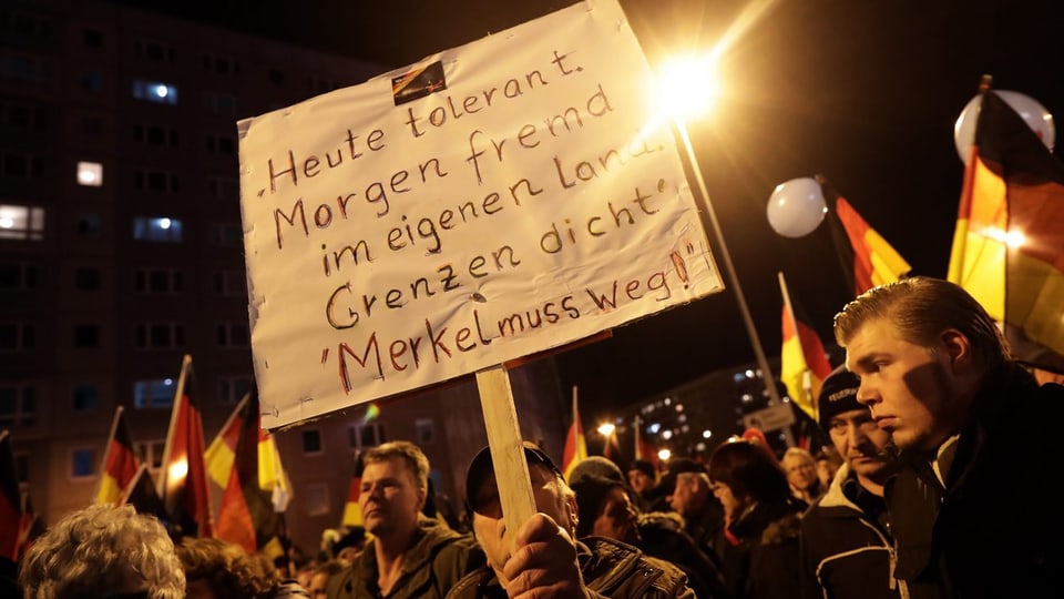 Demonstranten mit Anti-Merkel und -Toleranz-Plakat