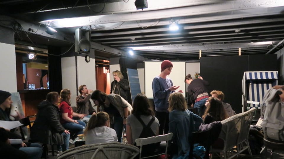 Jugendliche sitzend und stehend in einem Raum.