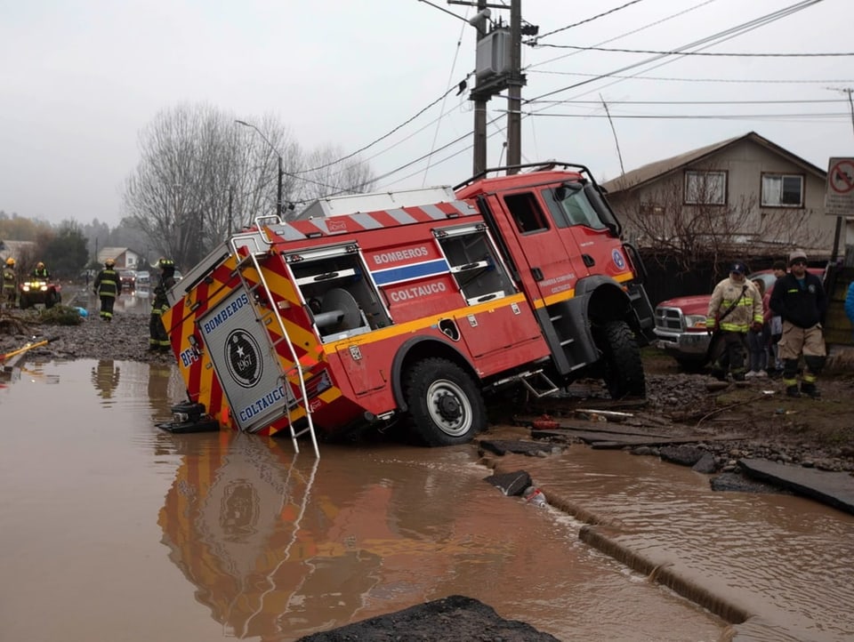 Feuerwehrauto in Schieflage, überschwemmte Strasse