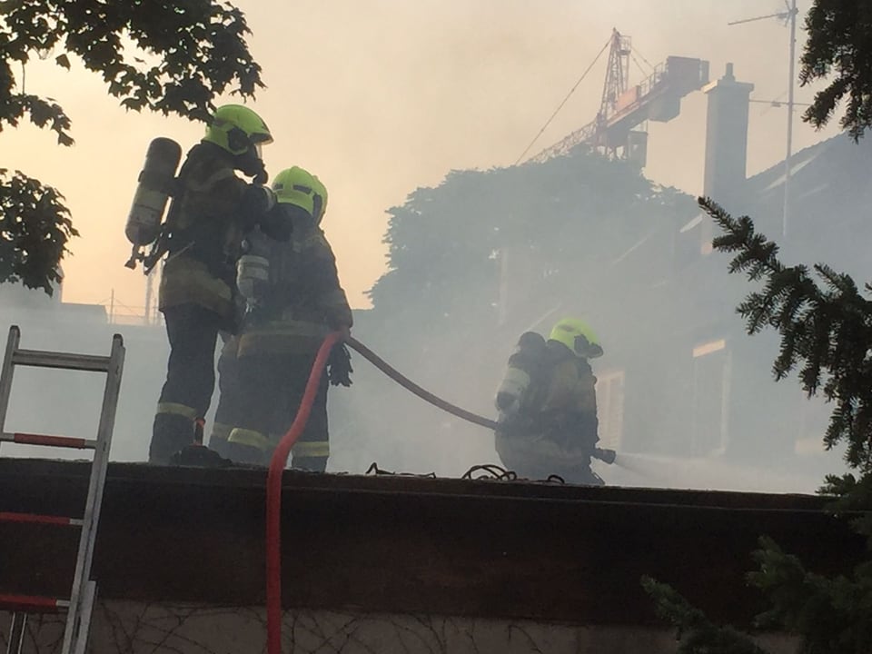 Feuerwehrmänner auf dem Dach am Löschen  